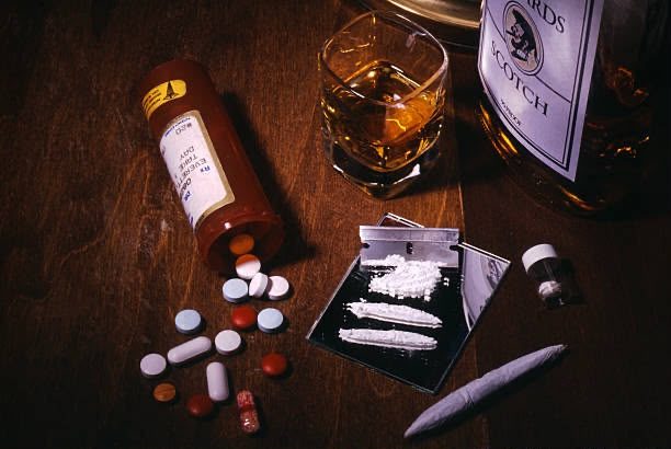 Alcohol and assorted drugs arranged on a dark wooden table