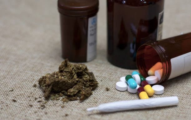 Cannabis, prescription tablets and pill bottles on a table